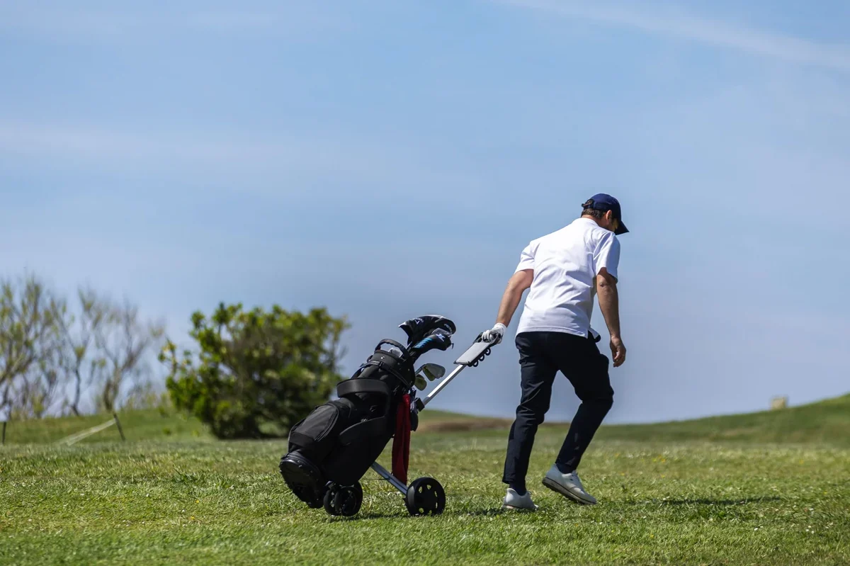 Una bolsa de golf asegurada en un carrito de empuje negro