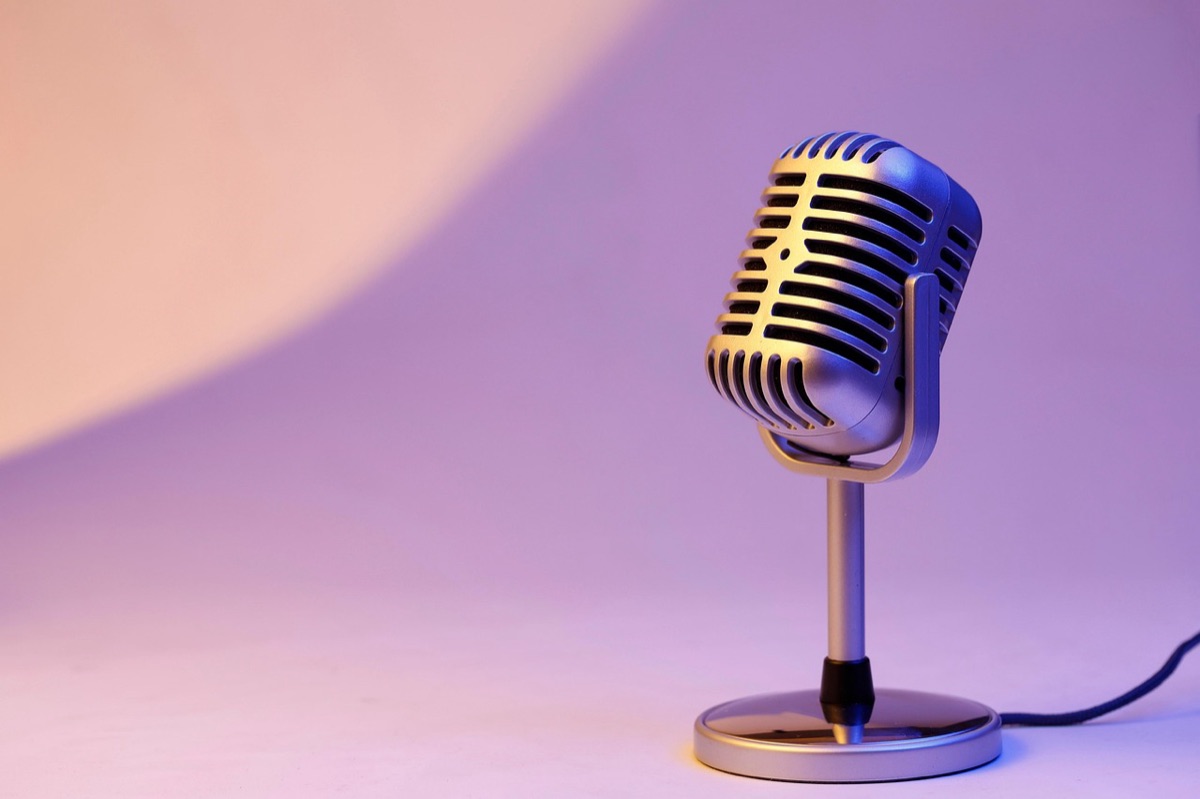 A classic vintage silver microphone on a dark stage with spotlighting