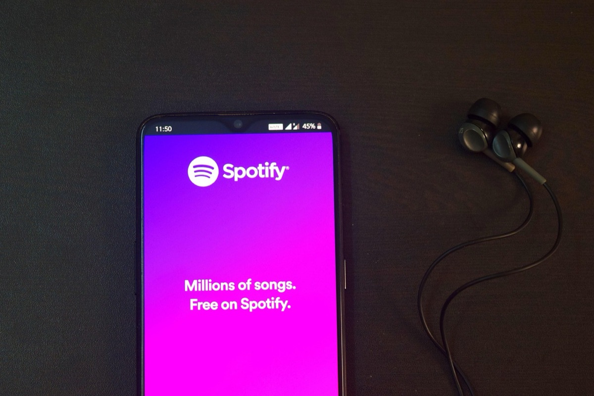 A person holding a smartphone displaying a music streaming interface