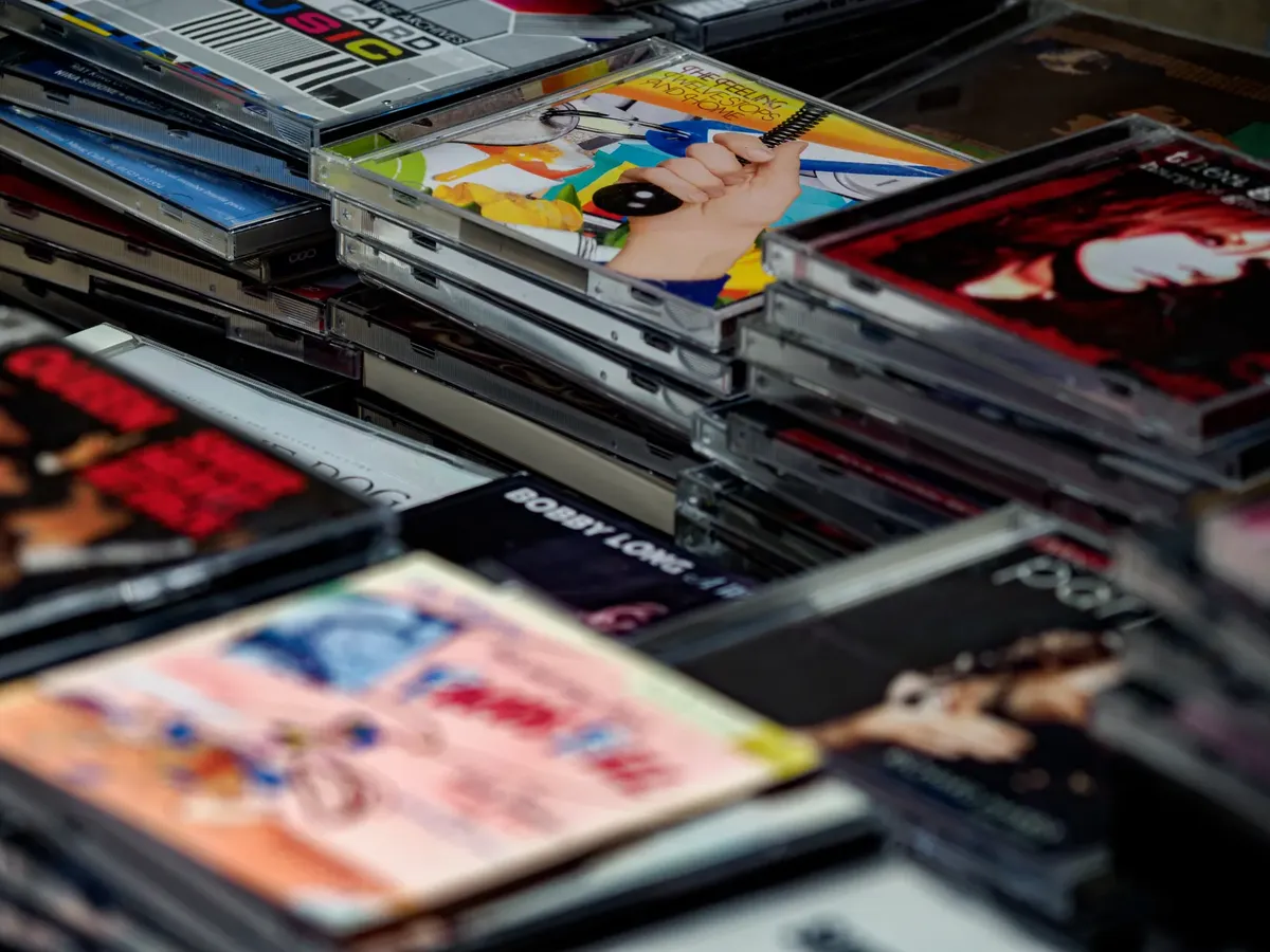 색상이 풍부한 음악 CD 여러 개가 플라스틱 케이스에 담겨 있으며, 다양한 앨범 썸네일을 보여주는 줌인 이미지.