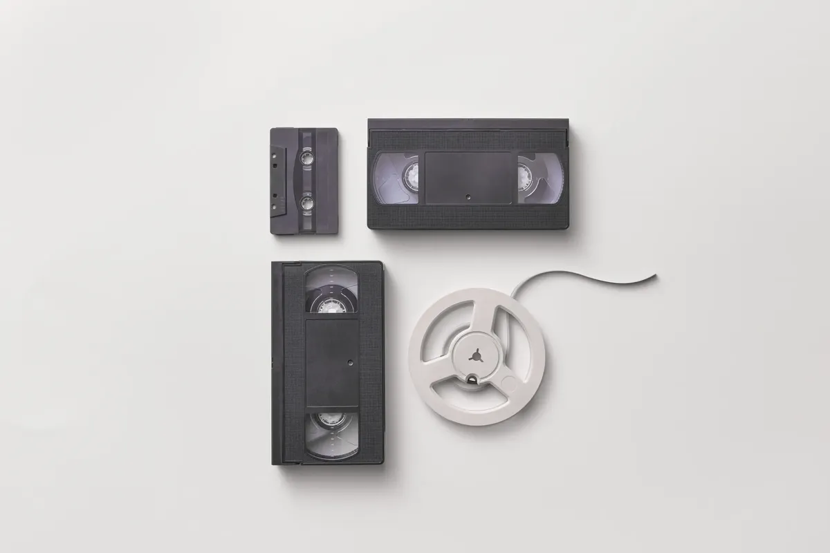 Collection of vintage audio and video tapes including VHS and cassette on a white background.
