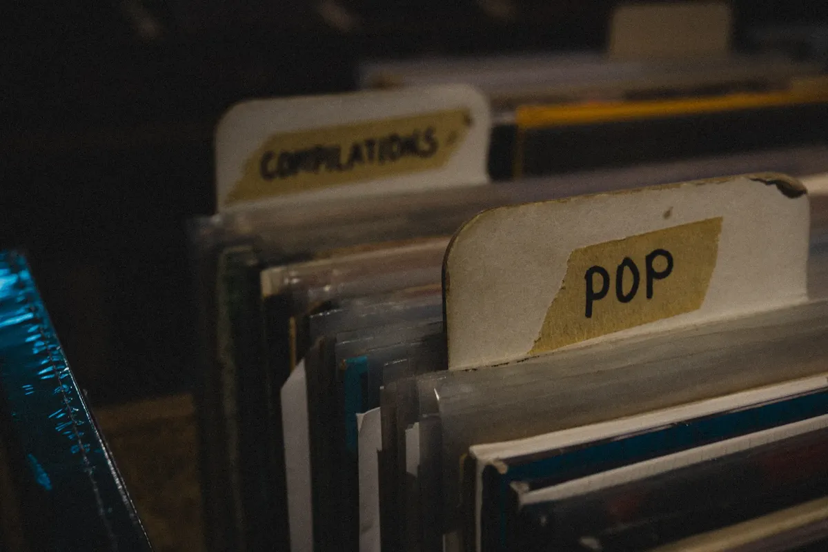 조명이 어두운 레트로 스토어에서 'POP' 및 'COMPILATIONS'로 분류된 베이스의 근접 촬영