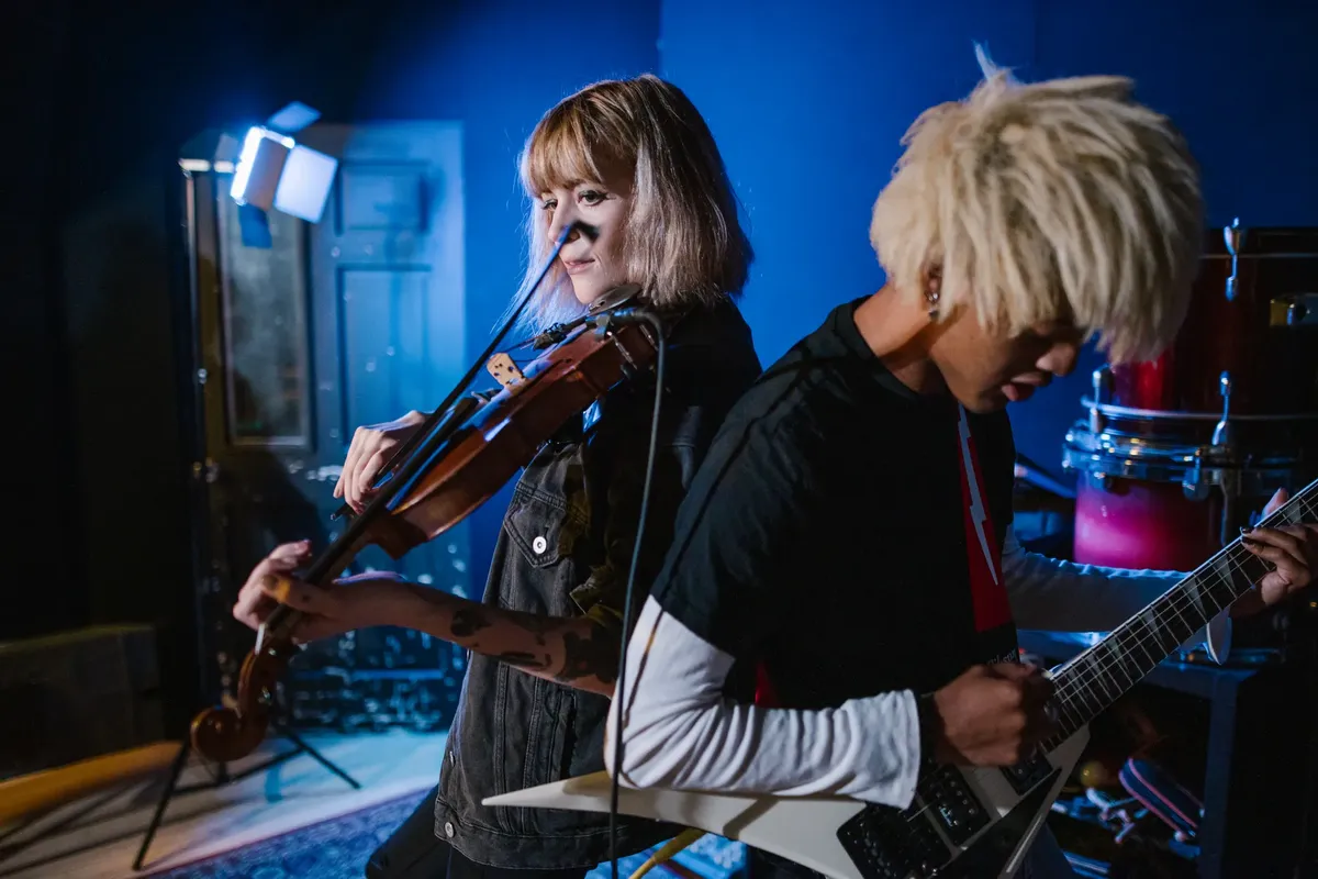 Energetic music rehearsal with violin and electric guitar under studio lighting.